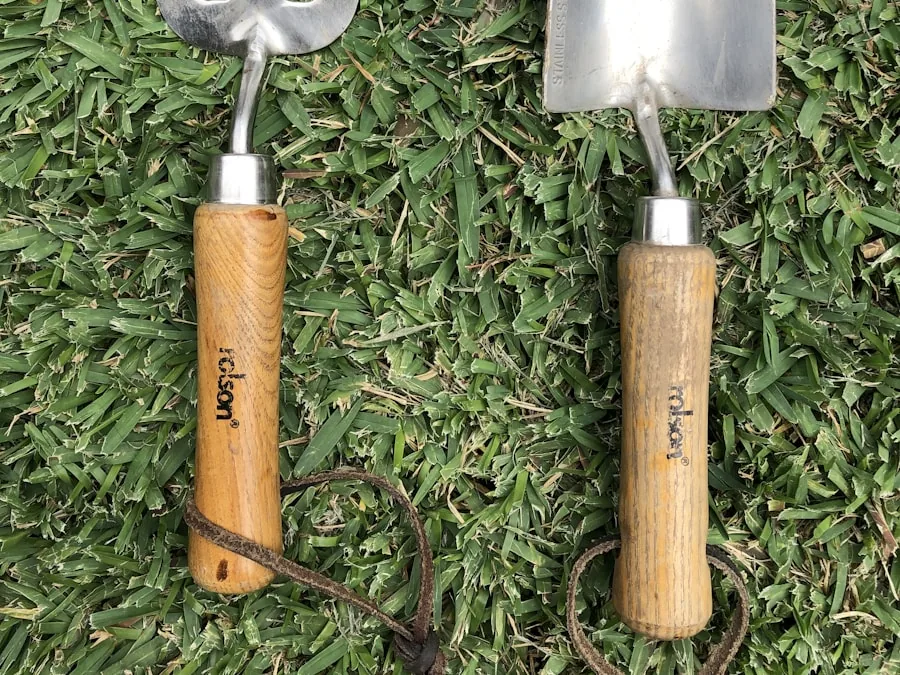 An ash-handled hand fork and trowel with wide cushioned grips, laid on cut grass.